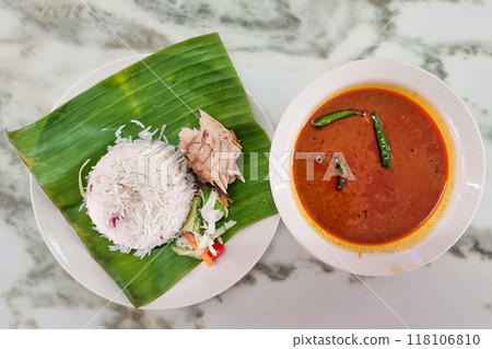 Overhead view on authentic simple Nasi Dagang, popular delicacy in Terengganu served with mackerel fish fillet, and with bowl of gravy next to it. Overhead view on authentic simple Nasi Dagang, popular delicacy in Terengganu served with mackerel fish fillet, and with bowl of gravy next to it. 118106810