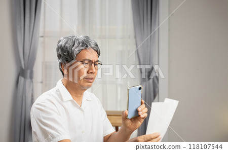 Senior man is paying bills via mobile phone. The bill payment is successful. 118107544