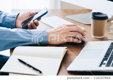 A man who operates a computer and a smartphone A man who operates a computer and a smartphone 118107668