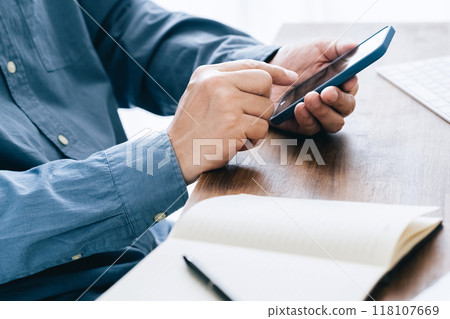 A man who operates a computer and a smartphone A man who operates a computer and a smartphone 118107669