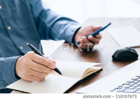 A man who operates a computer and a smartphone A man who operates a computer and a smartphone 118107673