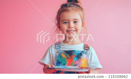 Portrait of a Happy cute little artist painting smiling girl holding a color palette in the studio with pastel pink background 118108662