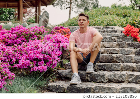 Handsome caucasian man sitting on the steps in summer garden. Handsome caucasian man sitting on the steps in summer garden. 118108850