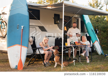 A happy family is resting nearby near their motorhome in the forest 118110030