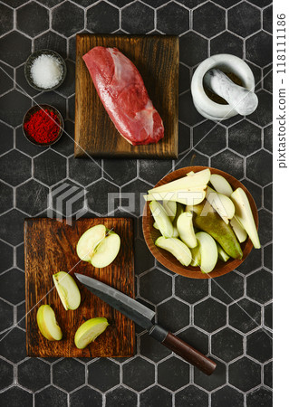 Top view of sliced apples and pears laid out on a chopping board next to the duck breast 118111186