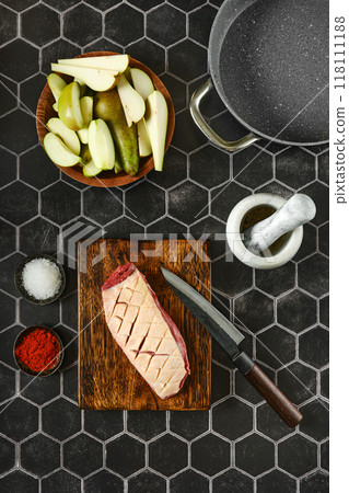 Overhead view of raw duck breast with the skin cut crosswise on wooden chopping board 118111188