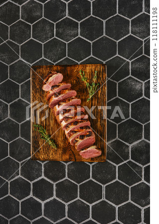 Top view of a seared duck breast cut on slices on wooden chopping board Top view of a seared duck breast cut on slices on wooden chopping board 118111198