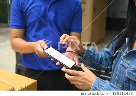 Young woman putting signature while receiving parcel box from delivery man Young woman putting signature while receiving parcel box from delivery man 118111438