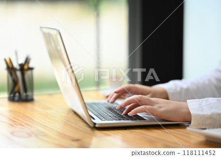Close up businesswoman hands typing on a laptop, remote work or search information 118111452