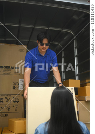 Male courier standing inside a truck, preparing to hand over package to a customer 118111459