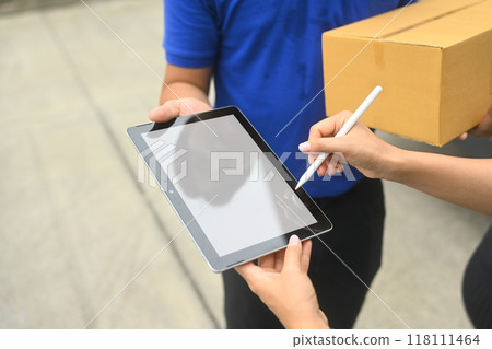 Cropped shot of delivery man taking electronic signature from customer. Shipping service concept Cropped shot of delivery man taking electronic signature from customer. Shipping service concept 118111464