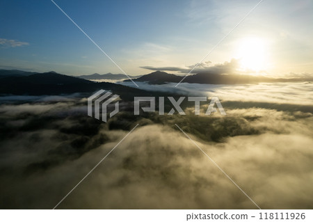Aerial view drone shot of flowing fog waves on mountain tropical rainforest,Bird eye view image over the clouds Amazing nature background with clouds and mountain peaks Aerial view drone shot of flowing fog waves on mountain tropical rainforest,Bird eye view image over the clouds Amazing nature background with clouds and mountain peaks 118111926