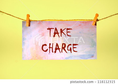 Conceptual take charge symbol. Copy space. TAKE CHARGE words written on a piece of paper in a clothespin on a rope on a yellow background Conceptual take charge symbol. Copy space. TAKE CHARGE words written on a piece of paper in a clothespin on a rope on a yellow background 118112315