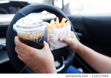 Asian woman driver hold and eat hamburger in car, dangerous and risk an accident. 118113564