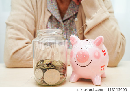 Retired elderly woman counting coins money with piggy bank and worry about monthly expenses and treatment fee payment. 118113603
