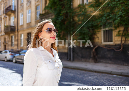 Young woman enjoying a sunny day on a historic street surrounded by charming architecture and greenery in the afternoon light Young woman enjoying a sunny day on a historic street surrounded by charming architecture and greenery in the afternoon light 118113853