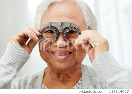 Asian senior woman wearing ophthalmic vision eye test and using optical trial frame. Asian senior woman wearing ophthalmic vision eye test and using optical trial frame. 118114057
