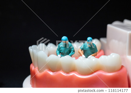 Miniature figurines of surgeons working on a large model of human teeth 118114177