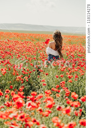 Woman poppies field. Back view of a happy woman with long hair in a poppy field and enjoying the beauty of nature in a warm summer day. 118114278