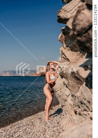 A woman is standing on a beach with her arms outstretched 118114294