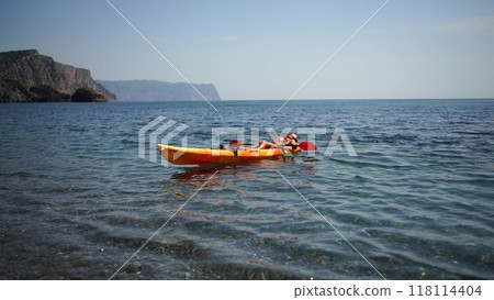A woman in a red bikini is laying on a kayak in the water A woman in a red bikini is laying on a kayak in the water 118114404