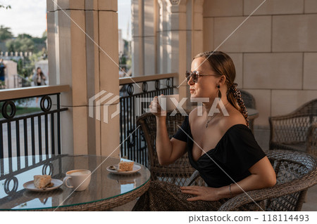 Woman, Balcony, Coffee. Woman enjoys a cup of coffee on a balcony overlooking a city. Woman, Balcony, Coffee. Woman enjoys a cup of coffee on a balcony overlooking a city. 118114493