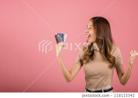 Portrait of Happy excited amazed Asian young woman holding bank card solution in hands in studio shot isolated on pink background, female smiling showing presenting credit card for online payment 118115342