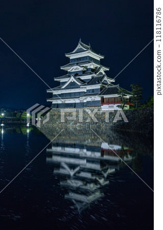 Matsumoto Castle, a national treasure in Matsumoto City, Nagano Prefecture, Japan. The main tower is lit up at night and reflects in the water of the inner moat. 118116786