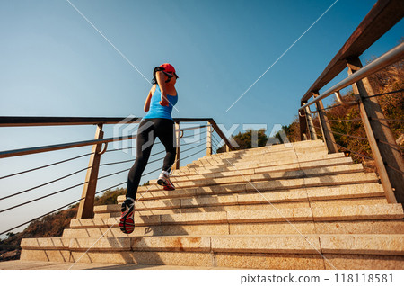 Healthy lifestyle sports woman running up on stone stairs at sunrise seaside 118118581