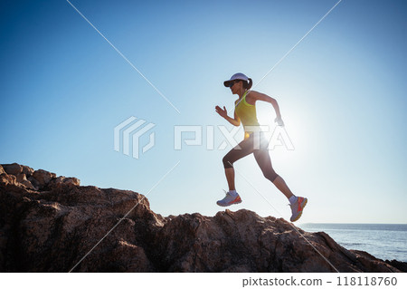 Woman runner running on sunrise seaside rocks Woman runner running on sunrise seaside rocks 118118760