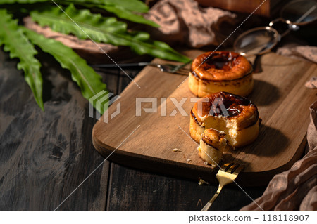 Close-up of two beautifully baked Basque cheesecakes served on a wooden plate 118118907