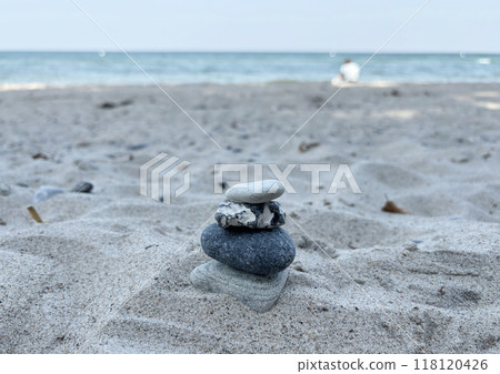 A scene of a man meditating after piling up stones of various natural shapes on a Baltic beach in summer 118120426