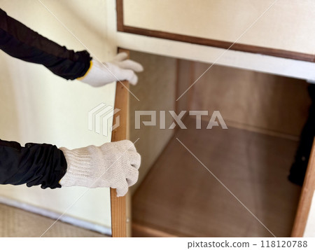 一隻戴著工作手套的手打開空衣櫃的門 118120788