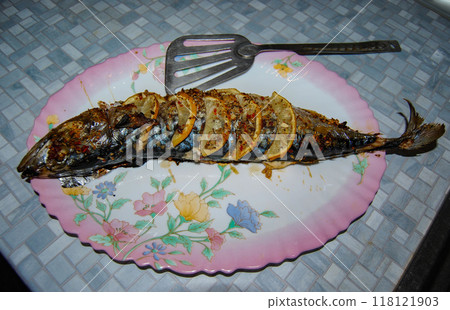 Baked mackerel on a plate. Golden Mackerel stuffed with lemon and sprinkled with spices. Baked mackerel on a plate. Golden Mackerel stuffed with lemon and sprinkled with spices. 118121903