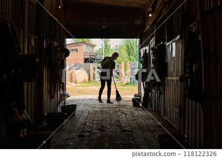 Person Sweeping Barn Floor at Horse Stable Person Sweeping Barn Floor at Horse Stable 118122326
