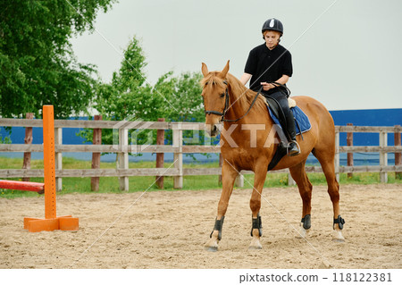 Young Rider Practicing Horseback Riding in Equestrian Arena Young Rider Practicing Horseback Riding in Equestrian Arena 118122381