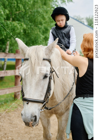 Child Riding Horse with Guidance from Trainer Outdoors 118122623