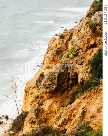 Steep, rugged cliffs overlooking the ocean, with textured rock formations and sparse vegetation Steep, rugged cliffs overlooking the ocean, with textured rock formations and sparse vegetation 118124285