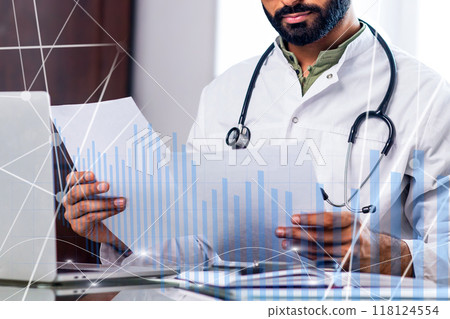 A doctor is looking at a computer screen with a graph on it 118124554