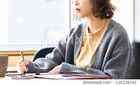 A woman taking notes with a serious expression A woman taking notes with a serious expression 118126142