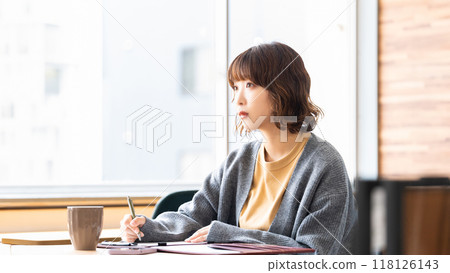 A woman taking notes with a serious expression A woman taking notes with a serious expression 118126143