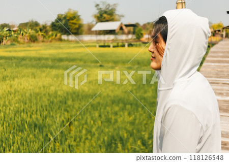 Woman resting at the rice fields after working out in the morning. Woman resting at the rice fields after working out in the morning. 118126548