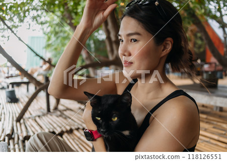 Woman play and hug relaxing with black cat in local bamboo cafe. Woman play and hug relaxing with black cat in local bamboo cafe. 118126551