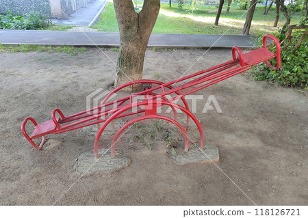 An old red swing for two in the yard near the house. An old red swing for two in the yard near the house. 118126721