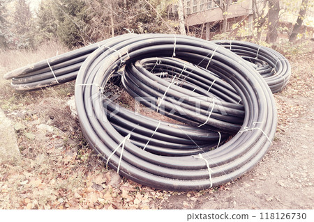 Pre-insulated pipe. A roll of plastic gas pipe is lying on a construction site. Pre-insulated pipe. A roll of plastic gas pipe is lying on a construction site. 118126730