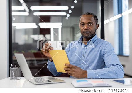 Office worker organizing documents while using laptop. Concept of efficiency, focus, and productivity in modern workspace. Worker demonstrates precision in handling paperwork. Office worker organizing documents while using laptop. Concept of efficiency, focus, and productivity in modern workspace. Worker demonstrates precision in handling paperwork. 118128054