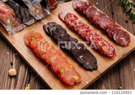 Sliced sausage with pistachios on wooden board, ideal for food presentations and gourmet displays Sliced sausage with pistachios on wooden board, ideal for food presentations and gourmet displays 118128981