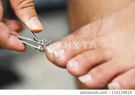 man is cleaning and cutting toenails 118129019