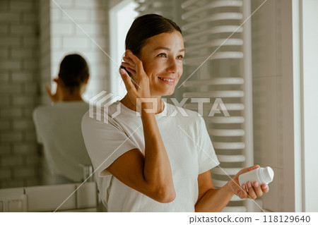 Skincare Routine A Woman Applying Cream in a Bright and Inviting Bathroom Space 118129640