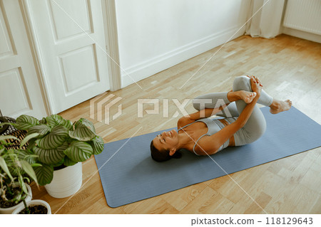 A woman practicing yoga in a calm, serene indoor space to enhance wellbeing and mindfulness A woman practicing yoga in a calm, serene indoor space to enhance wellbeing and mindfulness 118129643